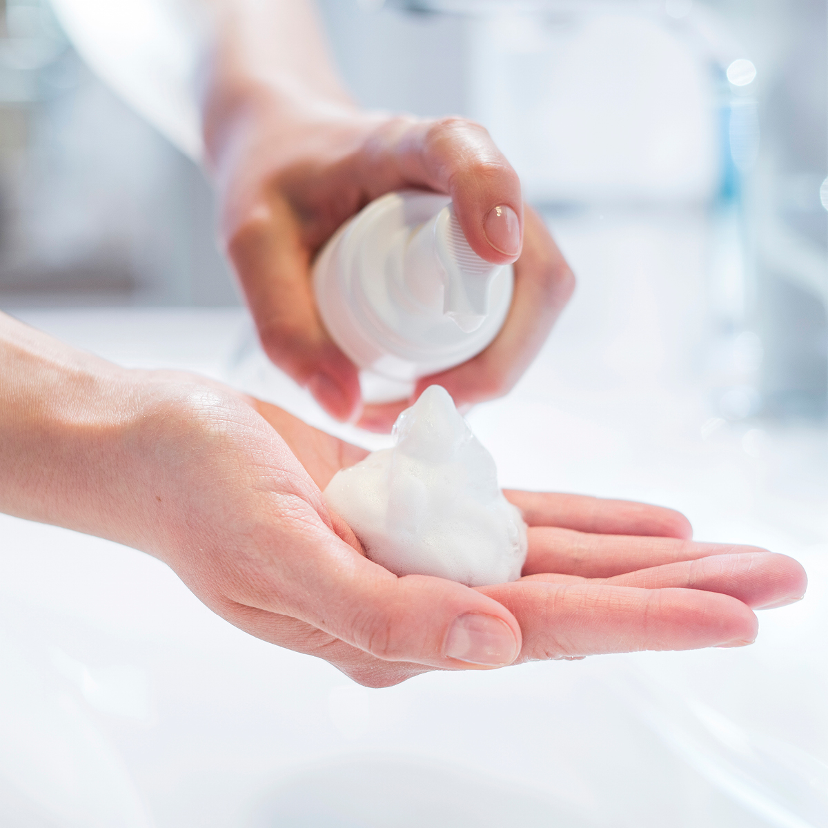 Hands applying a facial cleansing foam