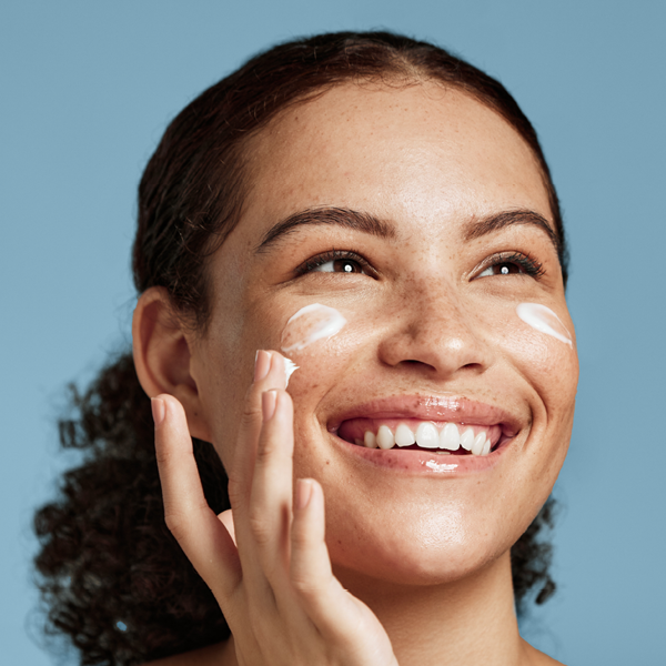 Vrouw die lacht smeert haar gezicht in met een crème