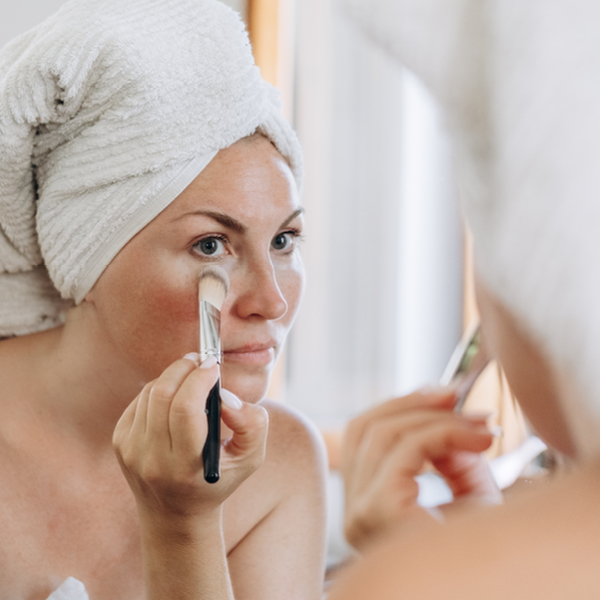 Vrouw doet make-up op haar gezicht met rode adertjes
