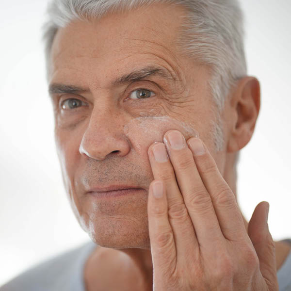 Een man smeert zijn wang in met crème.