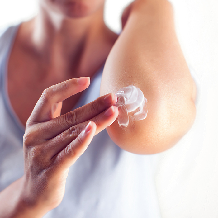 Vrouw smeert haar elleboog in met crème