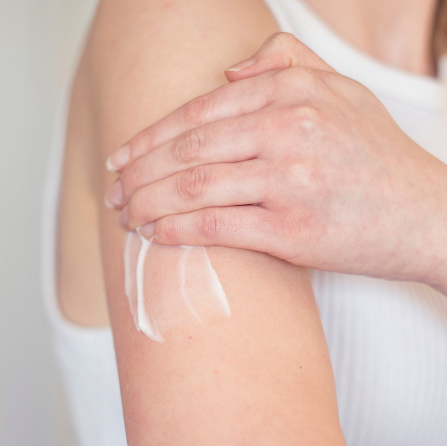 Una donna applica una crema sulla sua pelle secca