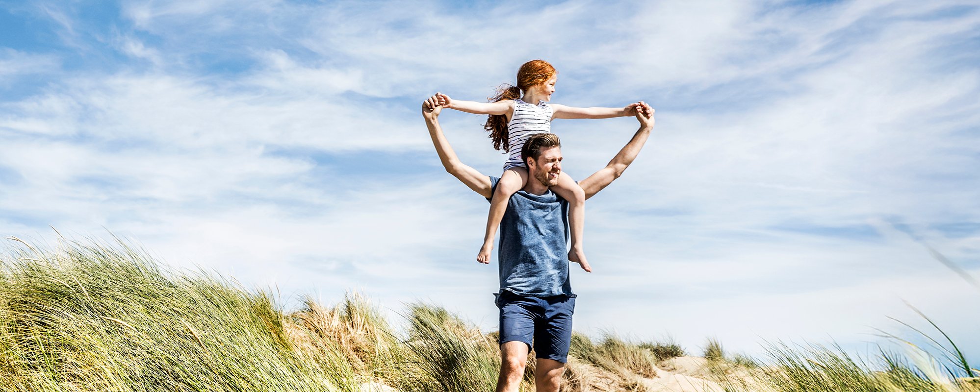Zonnige strandscène, vader met zijn dochter op zijn schouders