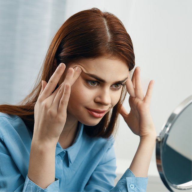 Vrouw raakt haar gezicht aan in de spiegel