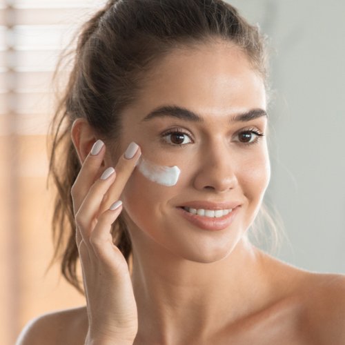 Jonge vrouw met crème op haar gezicht