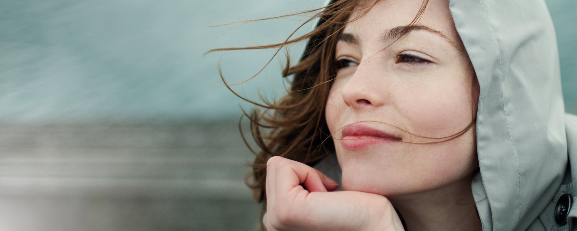 Woman with hair blowing in the wind, chin resting on hand