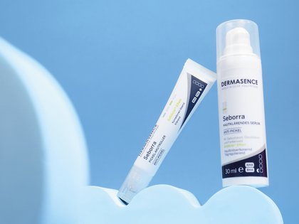 DERMASENCE Seborra Pimple relief roll-on en DERMASENCE Seborra Skin clarifying serum tegen een blauwe achtergrond