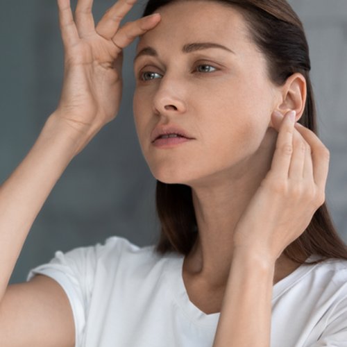Vrouw bekijkt haar droge huid in de spiegel