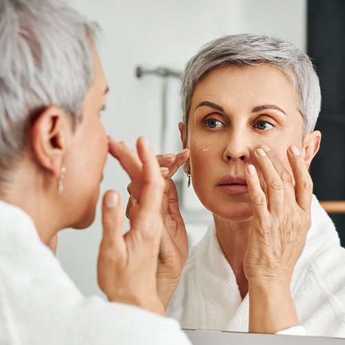 Vrouw kijkt in de spiegel naar haar dunner wordende huid