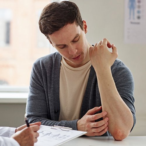 Patiënt die zijn psoriasis aan de dokter toont