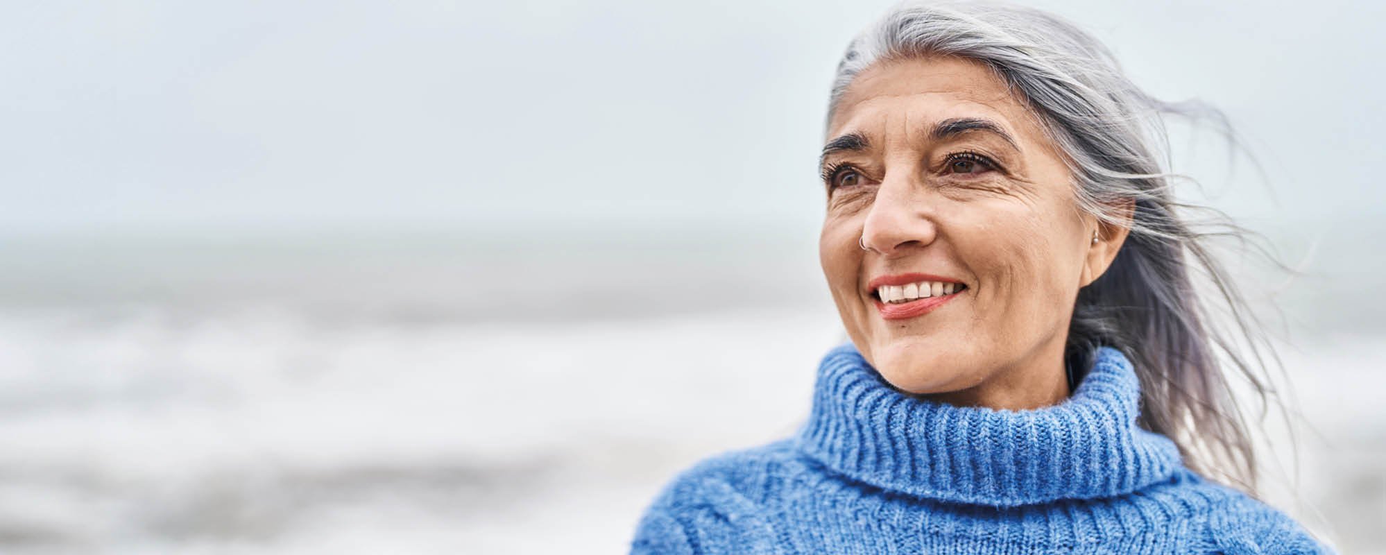 Grey-haired smiling woman on the beach