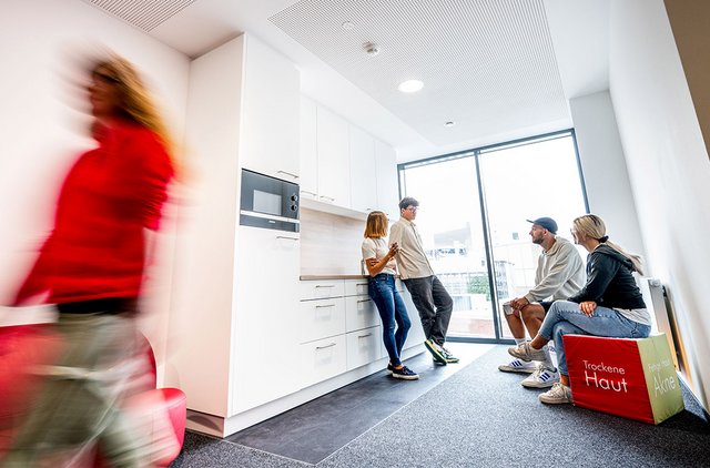 [Translate to Niederländisch:] DERMASENCE Küche mit plaudernden Mitarbeitenden