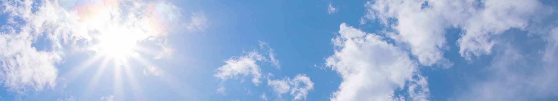 Zon en enkele wolken aan een blauwe hemel