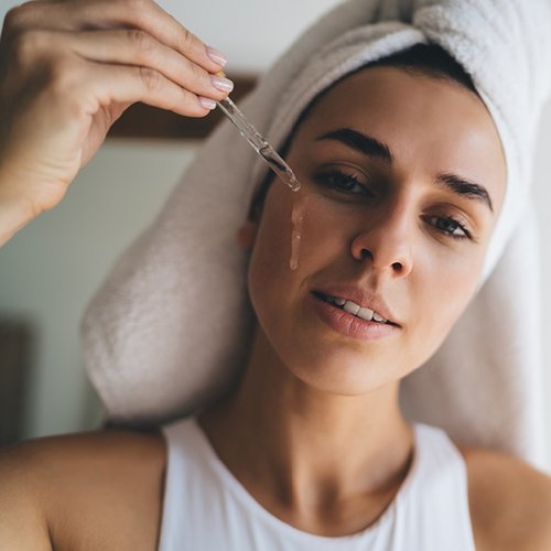 Vrouw brengt met een pipette retinol aan op haar wang
