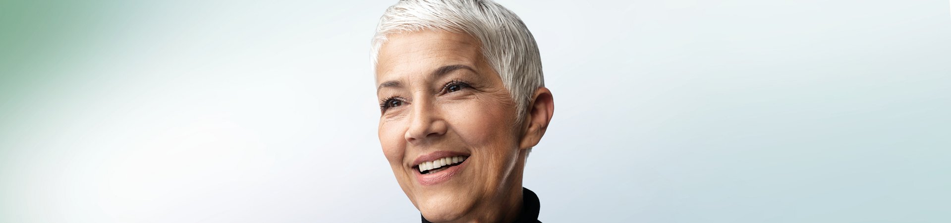 Lachende vrouw met kort haar voor een lichtblauwe achtergrond