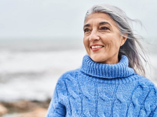 Grijze haren, glimlachende vrouw op het strand