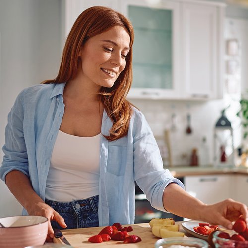 Een vrouw met rosacea snijdt fruit in de keuken